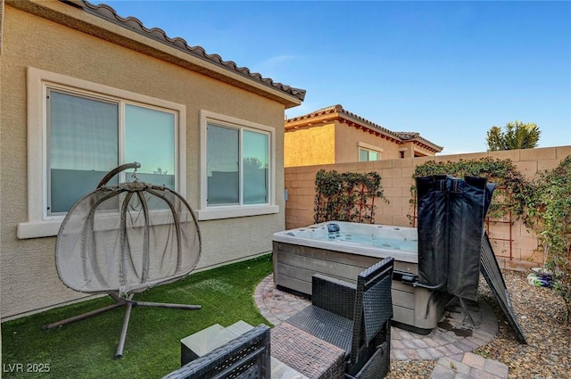 view of patio / terrace featuring fence and a hot tub