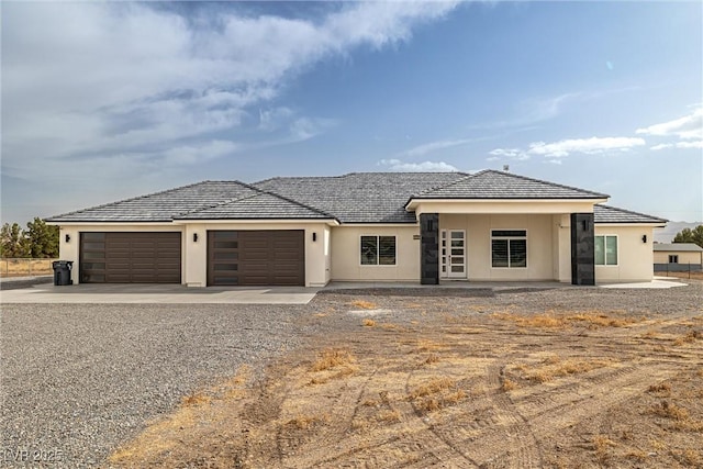 prairie-style house featuring a garage, concrete driveway, and stucco siding