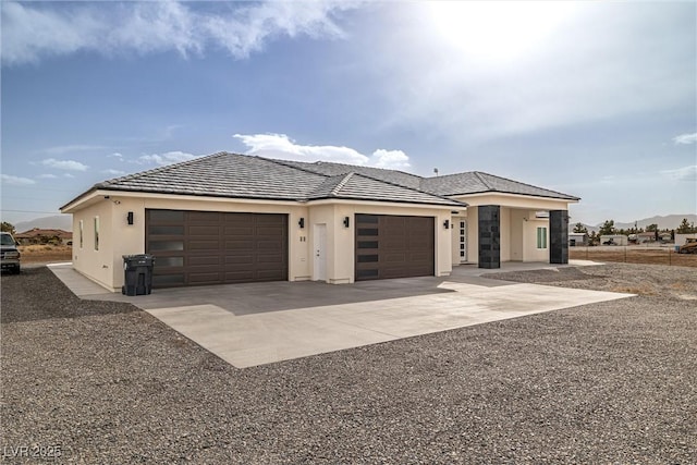 view of front of house featuring driveway, an attached garage, a tiled roof, and stucco siding