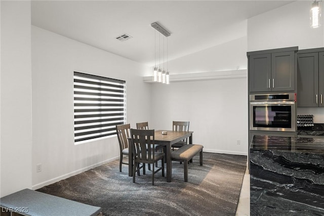 dining room with lofted ceiling, dark carpet, visible vents, and baseboards