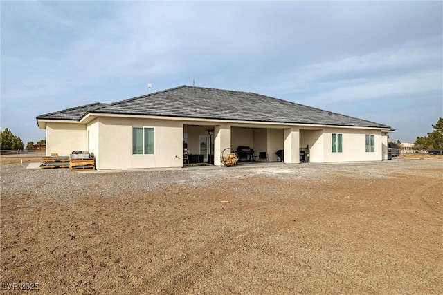 rear view of house featuring stucco siding