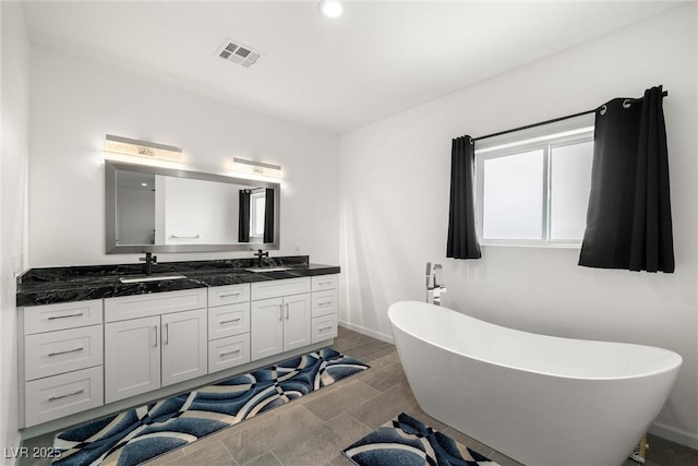 full bath featuring double vanity, a soaking tub, a sink, and visible vents