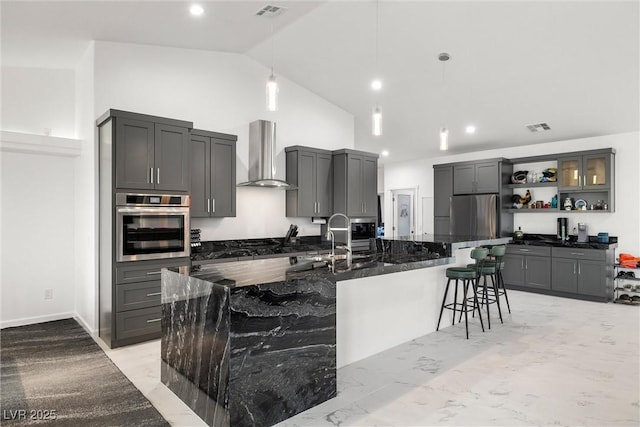 kitchen with a breakfast bar area, open shelves, stainless steel appliances, visible vents, and wall chimney exhaust hood