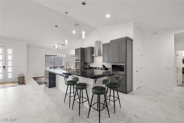 kitchen with stainless steel appliances, a spacious island, gray cabinets, a kitchen bar, and wall chimney exhaust hood