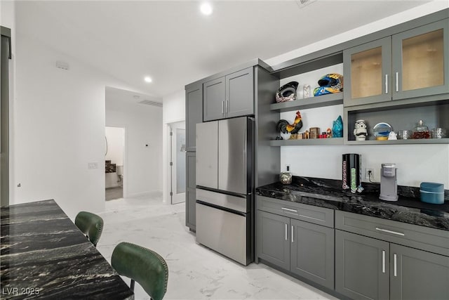 kitchen with freestanding refrigerator, marble finish floor, dark stone counters, and open shelves