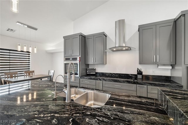 kitchen with visible vents, wall chimney exhaust hood, oven, gray cabinets, and a sink