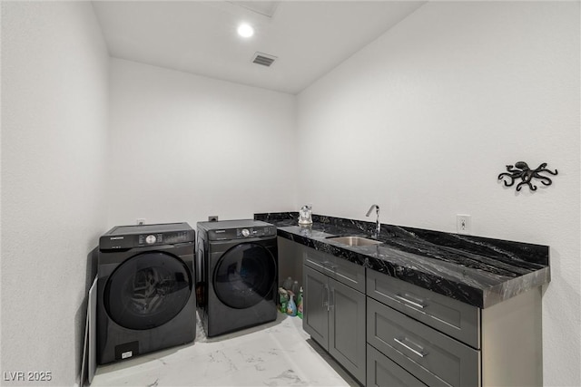 washroom with a sink, visible vents, marble finish floor, cabinet space, and washing machine and clothes dryer