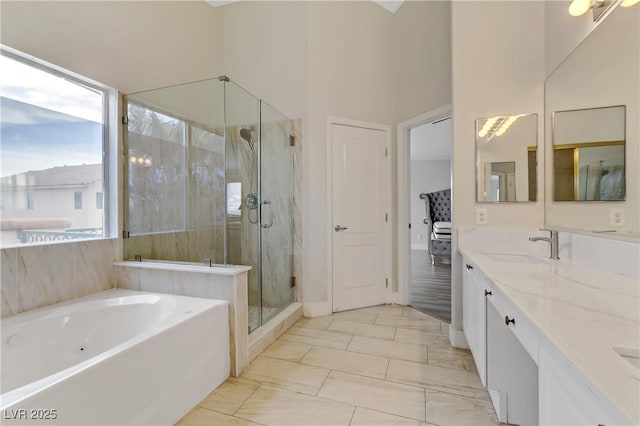 ensuite bathroom featuring double vanity, ensuite bath, a garden tub, a shower stall, and a sink