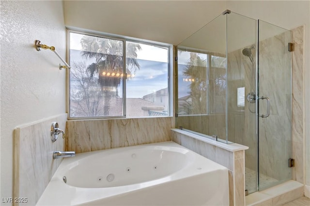 full bath featuring a marble finish shower, a tub with jets, and a textured wall