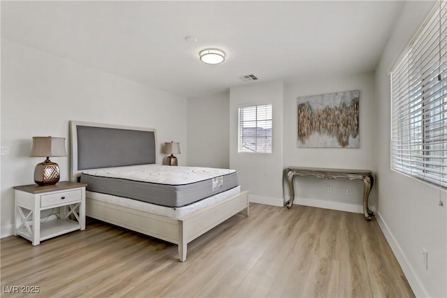 bedroom with light wood-style floors, baseboards, and visible vents