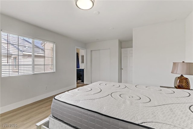 bedroom featuring light wood-style floors, baseboards, and a closet