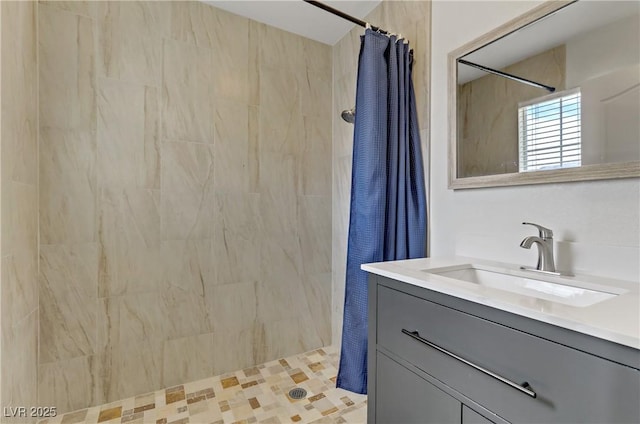 full bathroom with a tile shower and vanity