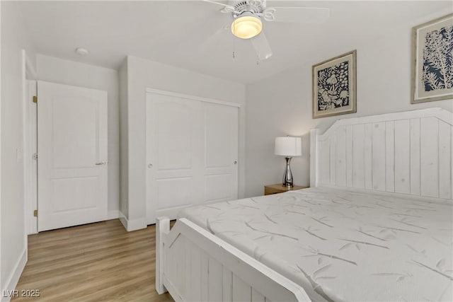 bedroom with light wood finished floors, baseboards, a ceiling fan, and a closet