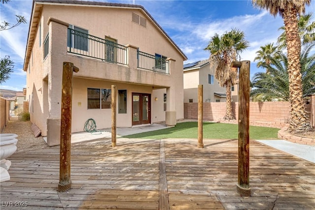 back of property featuring a balcony, fence, a deck, and stucco siding