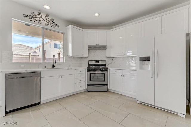 kitchen with under cabinet range hood, appliances with stainless steel finishes, light countertops, and a sink