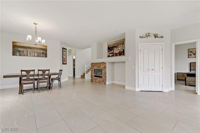 dining area with baseboards, a fireplace, and a notable chandelier