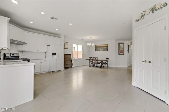 kitchen featuring decorative backsplash, white cabinets, under cabinet range hood, white fridge with ice dispenser, and a sink