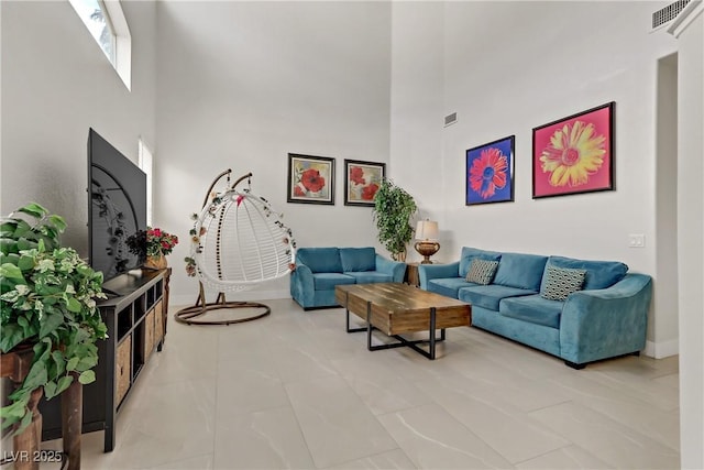 living area featuring baseboards, visible vents, and a high ceiling