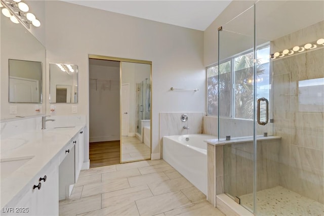 full bathroom featuring double vanity, a stall shower, a sink, and a bath