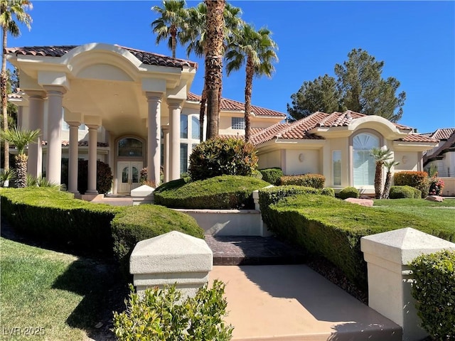 view of front facade with french doors, a tile roof, a front lawn, and stucco siding