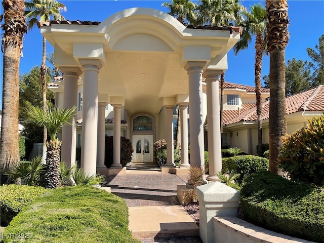 entrance to property featuring french doors, a tile roof, and stucco siding