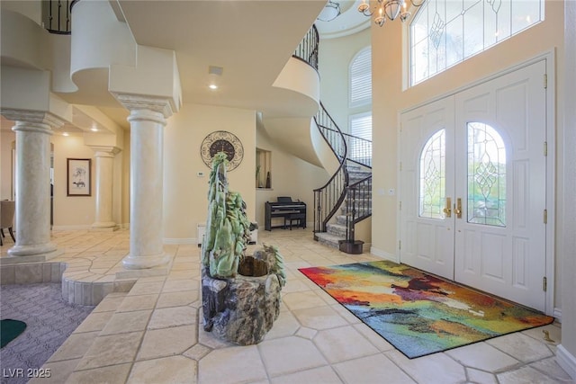 foyer with decorative columns, a towering ceiling, stairs, french doors, and light tile patterned flooring