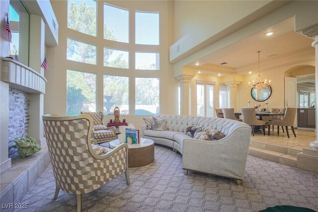 living room with tile patterned floors, plenty of natural light, decorative columns, and an inviting chandelier