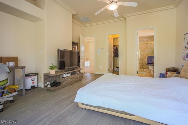 bedroom featuring ensuite bath, ceiling fan, wood finished floors, a spacious closet, and crown molding