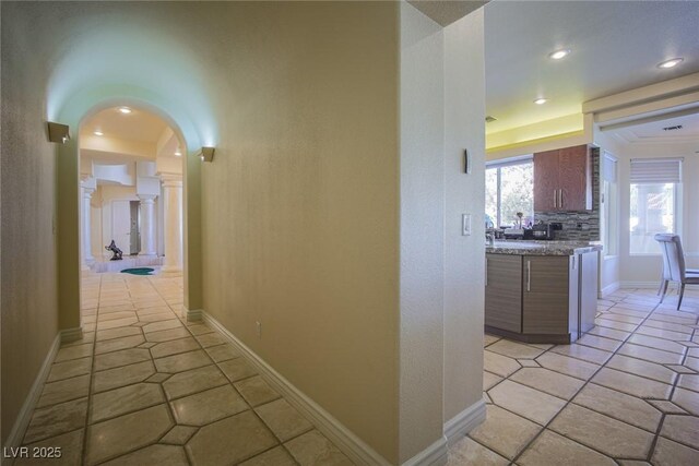 hallway featuring recessed lighting, baseboards, arched walkways, and light tile patterned flooring