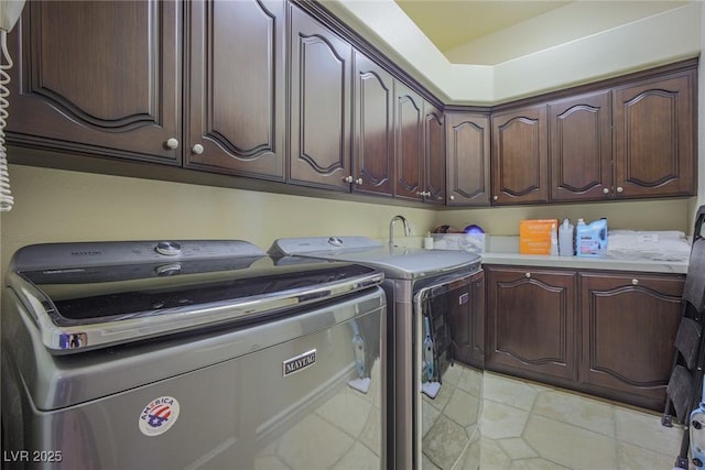 laundry room with light tile patterned flooring, washing machine and dryer, and cabinet space