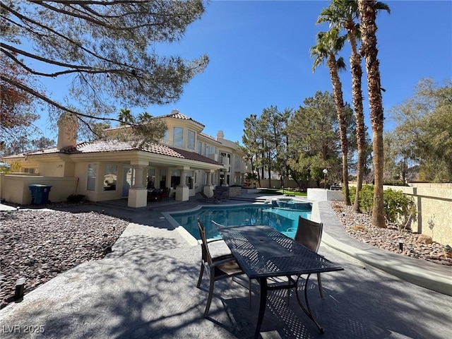 view of pool with a patio, fence, and a pool with connected hot tub