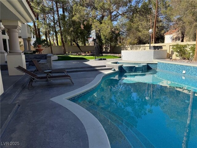 view of swimming pool featuring a patio area, a pool with connected hot tub, and a fenced backyard