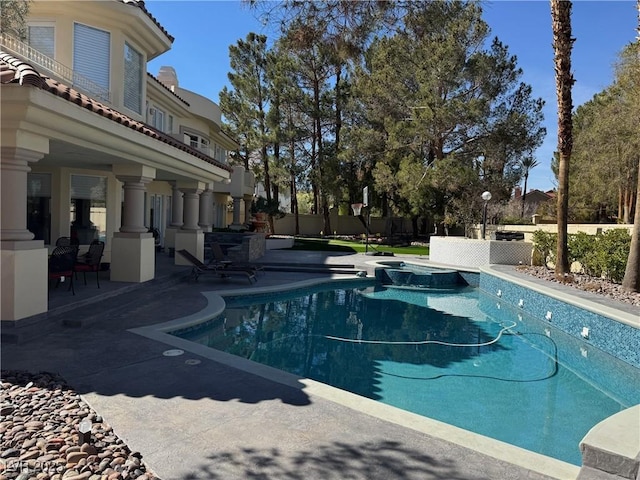 view of swimming pool featuring a pool with connected hot tub, a patio area, and fence