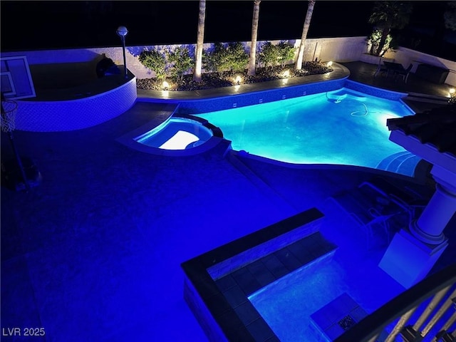 pool at twilight featuring a pool with connected hot tub