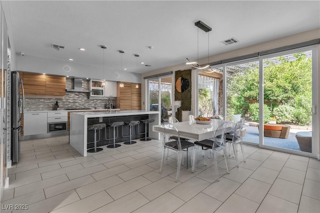 unfurnished dining area featuring light tile patterned floors, visible vents, a sink, and recessed lighting