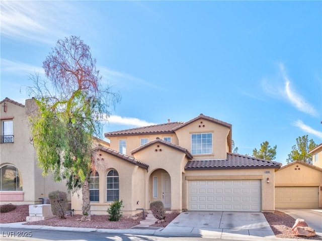 mediterranean / spanish-style house featuring concrete driveway, a tiled roof, and stucco siding