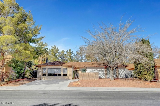 view of front of home featuring an attached garage, concrete driveway, and brick siding