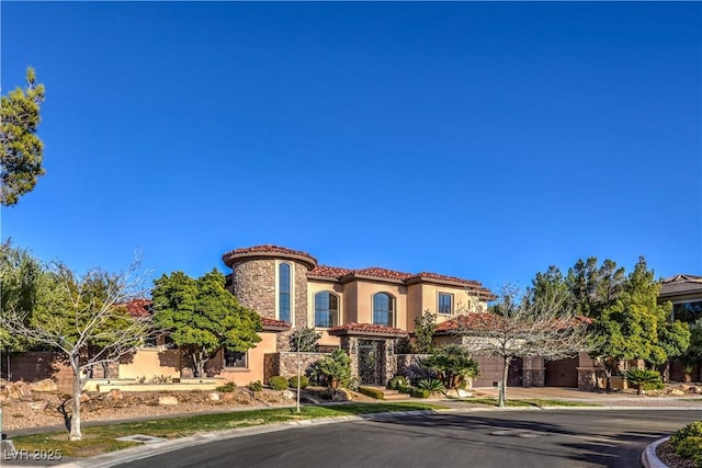 mediterranean / spanish-style home featuring stone siding, a tile roof, and stucco siding