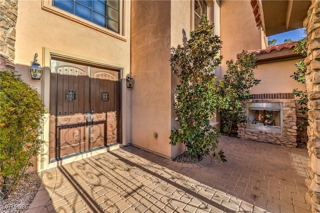 property entrance with stone siding, a tiled roof, a gate, and stucco siding