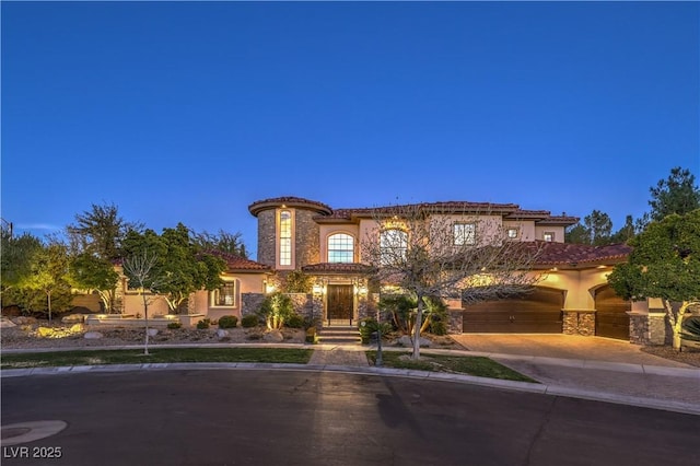 mediterranean / spanish-style house with stone siding, driveway, a tiled roof, and stucco siding