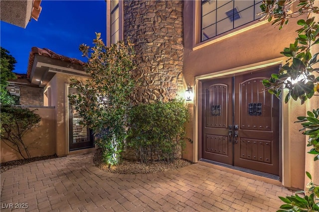 doorway to property with stone siding and stucco siding