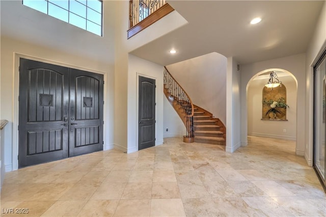 entryway with baseboards, stairway, arched walkways, and recessed lighting