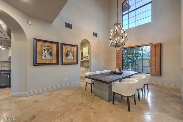 dining room featuring a healthy amount of sunlight, visible vents, arched walkways, and baseboards