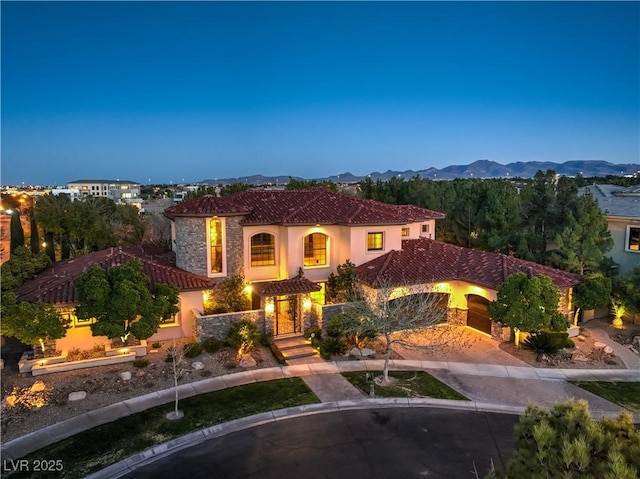 mediterranean / spanish-style house featuring stone siding, a mountain view, stucco siding, and a tiled roof