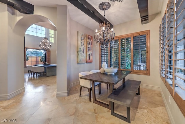 dining space featuring a notable chandelier, visible vents, a towering ceiling, beamed ceiling, and baseboards