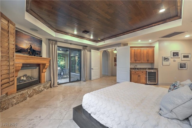 bedroom with a large fireplace, arched walkways, wood ceiling, access to outside, and a tray ceiling