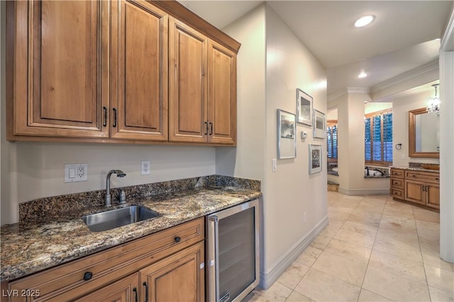 kitchen with beverage cooler, brown cabinets, a sink, and dark stone countertops