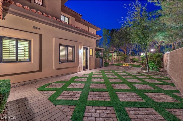 patio at night featuring a fenced backyard