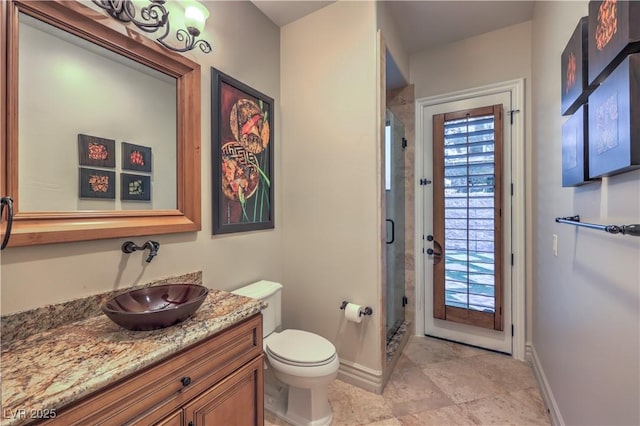 bathroom with toilet, a stall shower, baseboards, and vanity