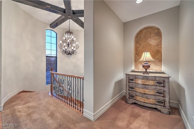 hall featuring a chandelier, carpet flooring, and baseboards